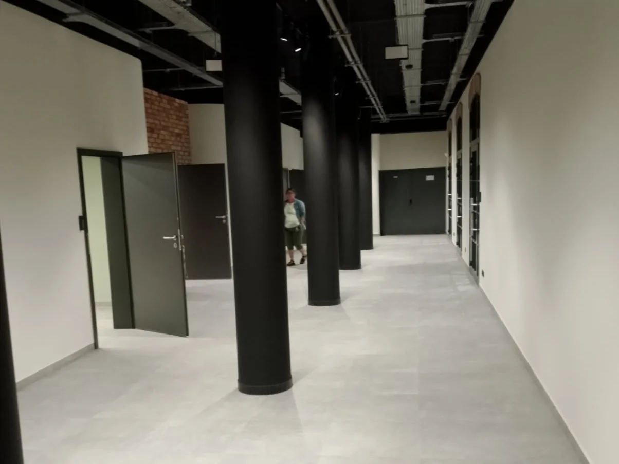Wnętrze po przebudowie: czarne słupy, instalacje pod stropem i nowa posadzka